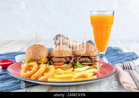 Drei Mini-Hamburger. Hausgemachte köstliche drei Mini-Burger mit Salat, Sauce und Zwiebelringen und pommes frites. Hausgemachte Mini-Burger-Schieberegler. Stockfoto