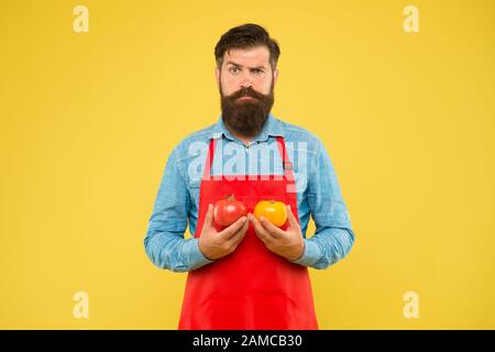 Lassen Sie Ketchup kochen. Bärtiger Koch mit Tomate. Gesunde Küche. Ernährung mit biologischem Essen. Vorteile für die Gesundheit von Tomaten. Nahrungsquelle für Vitamine. Brutaler Koch in der Schürze. Tipps zum Verzehr von Gemüse. Stockfoto