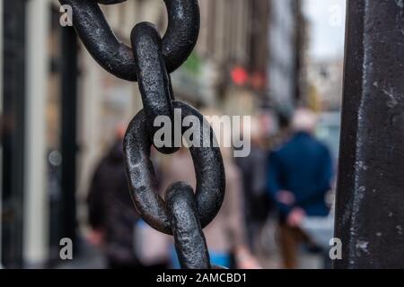 Riesige, große Metallkette in Schwarz mit vagen Menschen auf dem Hintergrund Stockfoto