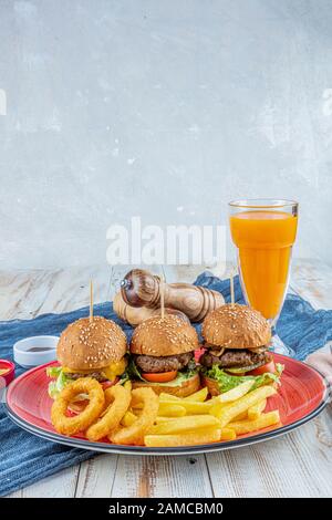 Drei Mini-Hamburger. Hausgemachte köstliche drei Mini-Burger mit Salat, Sauce und Zwiebelringen und pommes frites. Hausgemachte Mini-Burger-Schieberegler. Stockfoto