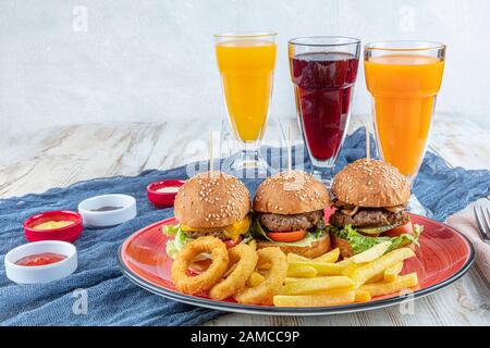 Drei Mini-Hamburger. Hausgemachte köstliche drei Mini-Burger mit Salat, Sauce und Zwiebelringen und pommes frites. Hausgemachte Mini-Burger-Schieberegler. Stockfoto