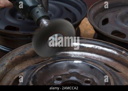 Entfernen Sie den Rost von der alten Fahrzeugrand mit einer Drahtbürste, die an der Bohrmaschine befestigt ist. Stockfoto