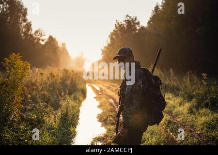 Sommerjagd bei Sonnenaufgang. Jäger bewegt Sich Mit Shotgun und Sucht Nach Beute Stockfoto