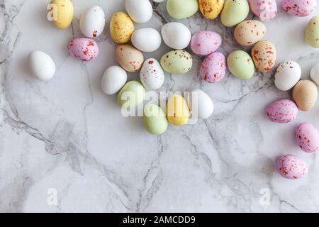 Frohe Ostern Konzept. Vorbereitung für den Urlaub. Ostern Eier in Pastellfarben Süßigkeiten Schokolade Bonbons auf trendige grauem Marmor Hintergrund. Einfache Minimalismus flach Ansicht von oben kopieren Raum Stockfoto