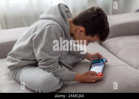 Videospielkonsole für Heim- oder tragbare Spiele. Teenager Mann spielt Spiel auf Konsole. Stockfoto