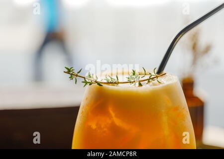 Nahansicht oben auf einem Glas kaltem Zitroneneis-Tee mit Strohhalm und Perücke über schaumigem und unscharfem Hintergrund der Straße im Freien. Stockfoto