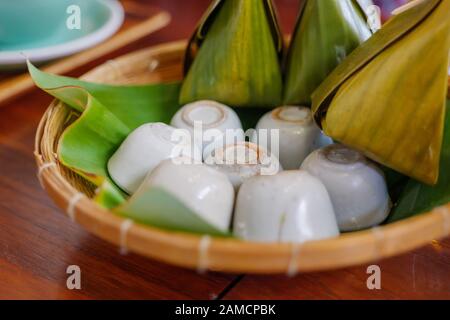 Thailändischer Coconut Milk Custard, Khanom Thuai, traditionelles thailändisches Dessert, serviert in kleinen Tassen auf Bananenblatt und Bambuskorb. Stockfoto