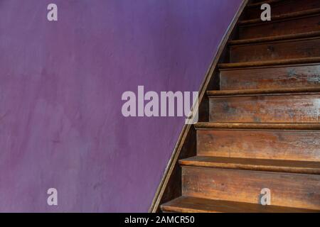 Eine alte Holztreppe gegen eine violette Wand Stockfoto
