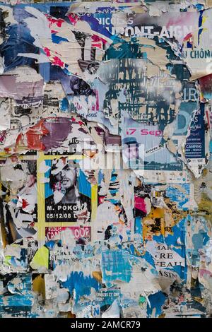 Eine Mauer auf der Straße mit unzähligen Anzeigen, die meisten von ihnen gerissen und zerrissen. Stockfoto