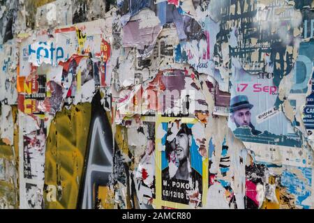 Eine Mauer auf der Straße mit unzähligen Anzeigen, die meisten von ihnen gerissen und zerrissen. Stockfoto