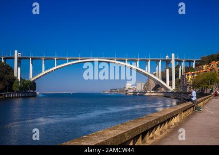Porto, PORTUGAL - MAI 2018: Mann, der in der Nähe der Flussmünde des Douro und der Arrabida-Brücke in einem schönen frühen Frühlingstag in Porto City im Portu fischt Stockfoto