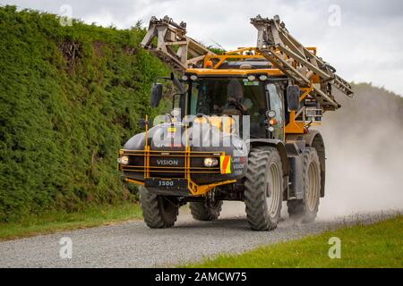 Canterbury, Neuseeland, 10. Januar 2020: Eine Feldspritze, die auf einer Schotterstraße in einem ländlichen Gebiet zu einem landwirtschaftlichen Beruf übergeht Stockfoto