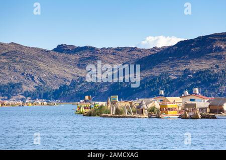 Schwimmende Inseln von Uros, Titicacasee, Peru, Südamerika - 2019-12-01. Blick auf die Insel, ein Boot vom Schilf, blauer Himmel in den Wolken Stockfoto