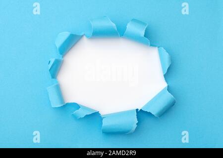 Blaues Papier mit geripptem Loch im mittleren Hintergrund Stockfoto