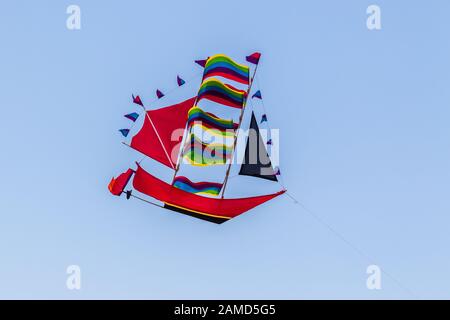 Rainbow Coloured Kite in Form eines hohen Schiffes am Himmel, Bali, Indonesien. Stockfoto