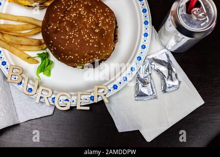 Leckere Burger mit Pommes auf einem weißen Teller. Wort Burger auf der Platte. Stockfoto