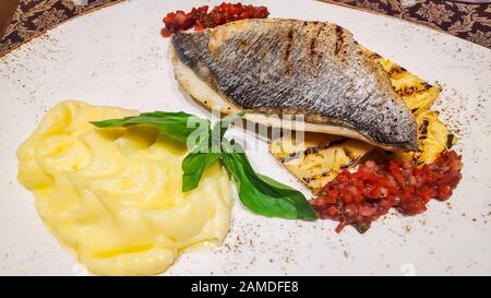 Gebratenes norwegisches Skrei-Kabeljau-Fischfilet mit Kartoffelpüree, Pilz und Zitronenschurze als Nahaufnahme auf einem modernen Designerplättchen Stockfoto