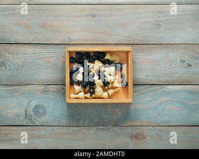 Schachfiguren aus Kunststoff in eine Holzkiste mit Holz- Hintergrund Stockfoto