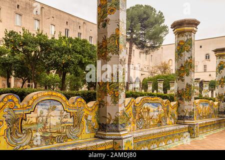 Neapel, ITALIEN - 4. JANUAR 2020: Sonnenlicht beleuchtet die Rokoko-Majolikafliesen des Kreuzgangs des monumentalen Komplexes von Santa Chiara Stockfoto