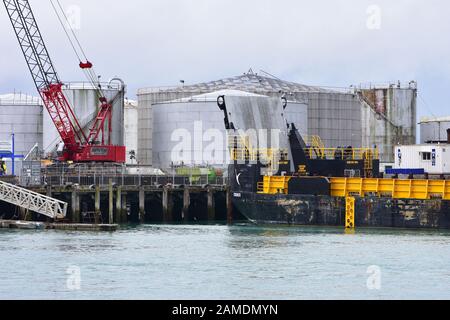 Kahn an Industriesteg mit großen zylindrischen Silos und Kran gebunden. Stockfoto