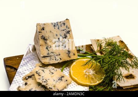 Geschnittener Weichkäse mit edler blauer Form auf einem Schneidebrett mit einem Dill, einer Zitronenbrot- und Kita-Scheibe Stockfoto