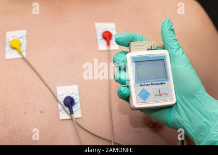 Die Hand des Arztes, der holter-herzmonitor auf die Brust eines jungen Mannes aufgibt Stockfoto