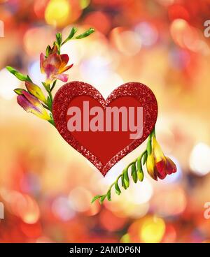 Frische rote und gelbe Freesienblüten und glitzerndes Herz in Anordnung zum Valentinstag auf farbenfrohem weichem Hintergrund. Stockfoto