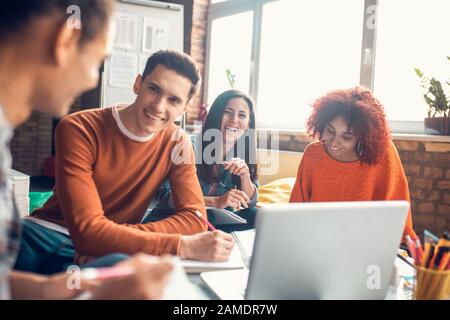 Studenten lachen, während sie gemeinsam Zeit genießen und sich auf Prüfungen vorbereiten Stockfoto