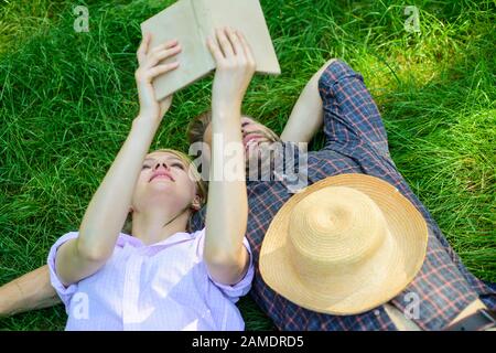 Mann und Mädchen legen sich auf Gras und haben Spaß. Liebespaar verbringt Freizeit mit dem Lesen von Büchern. Paar Seeleute zu romantischen Terminen. Romantische Paar-Studenten genießen Freizeit mit Poesie oder Literaturrasen im Hintergrund. Stockfoto