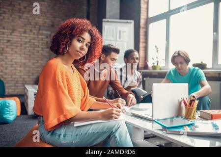 Geschweifte mulatto Studenten fühlen sich gut, während sie mit Freunden lernen Stockfoto