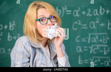 Wissensdurst. Hungrig nach Wissen. Sie ist bereit, ihre Unterlagen zu essen. Frauenlehrerin isst zerknitterten Papier-Schwarzen-Board-Hintergrund. Lehrer isst Papier mit fehlgeschlagener Prüfung. Stockfoto