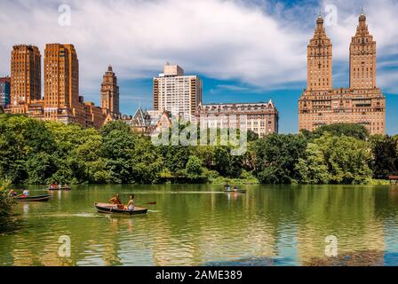 NYC, NY/USA - 12. Juli 2014: Die Menschen Reihen sich im Central Park mit der Upper West Side Manhattan Skyline im Hintergrund. Stockfoto