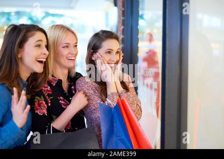 Aufgeregtes Mädchen, das beim großen Einkaufen auf das Schaufenster schaut Stockfoto