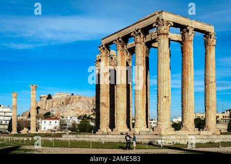 Blick auf den Tempel des olympischen Zeus mit den 16 erhaltenen Säulen, von denen eine auf dem Boden liegt. Akropolis ist im Hintergrund. Stockfoto