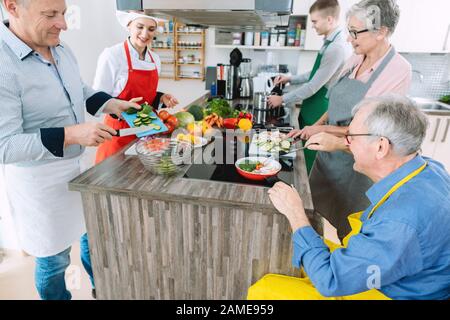 Küchenchef zeigt Auszubildenden die Geheimnisse des gesunden Kochens in ihrer Küche Stockfoto