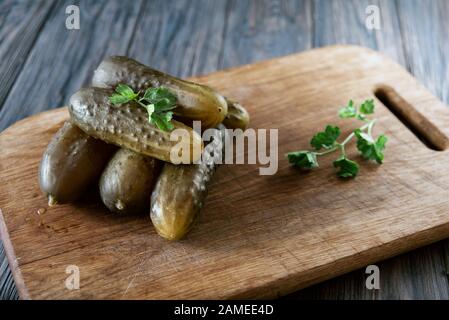 Marinierte Gurken gherkins. Eingepickte Gurken mit Petersilie in einer Schüssel vor dunklem rustikalem Hintergrund. Gesalzene Gurken - eine der traditionellen Slavi Stockfoto