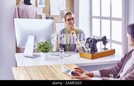 Attraktive Mode Designer arbeiten im Büro, lehnte sich auf dem Schreibtisch, Zeichnung Stockfoto