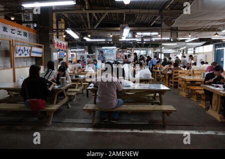 Familien und Menschen, die Thunfisch, Sushi und frische Meeresfrüchte auf dem Fischmarkt in Shiogama, Präfektur Miyagi, Japan, Asien essen. Japanische Kultur und Tradition Stockfoto