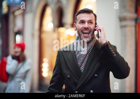 Aufgeregter reifer Mann ist am Telefon Stockfoto