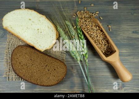 Frische Ähren und Weizenkörner mit geschnittenem Weiß- und Braunbrot oder Vollkornbrot auf hessisch auf einem rustikalen Holztisch, von oben betrachtet als Flachlage Stockfoto