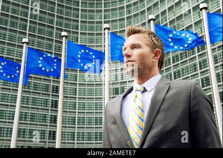 Ernsthaften europäischen Geschäftsmann stand vor einer Reihe von EU-Flaggen Stockfoto