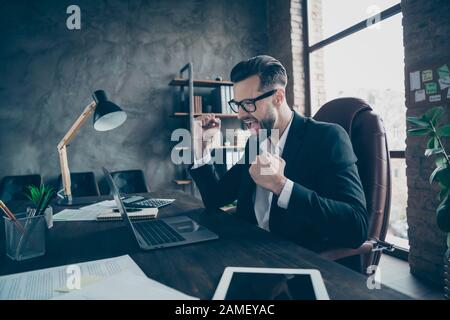 Profilfoto von gut aussehenden Unternehmern, die die Fäuste halten, die zum Feiern des Erfolgs des neuen Unternehmensprojekts erhoben wurden, trägt Specs Black Blazer Hemdanzug Stockfoto