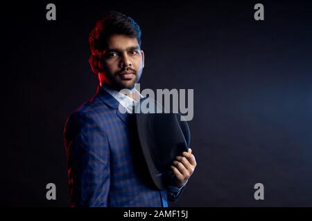 Nahaufnahme des jungen, gutaussehenden, seriösen und bärtigen Indianers, Geschäftsmann mit stilvoller Frisur, Hemd, kariertem Anzug im Stand ag Stockfoto