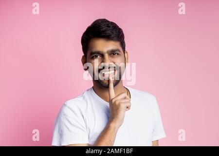 Horizontales Nahporträt von gut aussehenden jungen indischen Männern, Studenten mit weißem T-Shirt, Blick auf die Kamera mit breitem Lächeln, Index Stockfoto