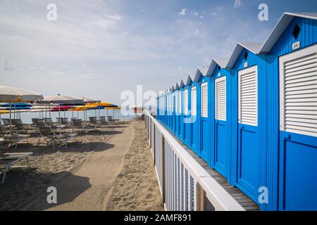 Traditionelle italienische Strandhütten an einem sonnigen Tag, Blaue Strandhütten in Reihen an der Küste angeordnet, Varazze Liguria Italien. Stockfoto