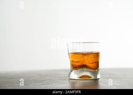 Glas goldener Whisky im Alter mit Eiswürfeln auf dem Tisch. Orangefarbenes Alkoholgetränk mit Felsen an der Bar Stockfoto