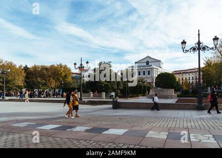 Madrid, Spanien - 1. November 2019: Plaza de Oriente im historischen Zentrum. Menschen, die im Herbst gegen das Royal Theatre spazieren Stockfoto