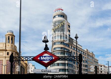 Madrid, Spanien - 1. November 2019: U-Bahn-Schild in der U-Bahn-Station Callao vor dem Kapitolgebäude auf dem Hintergrund in der Gran Via Avenue Stockfoto