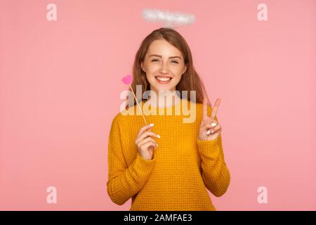 Valentinstag. Porträt eines lieblichen süßen Ingwermädchens mit Halo über Kopf, das pinke Papierlippen auf Stock hält, Symbol für Kuss und Liebe, die den Sieg ge zeigen Stockfoto