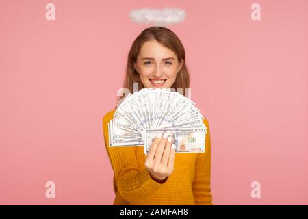 Großes Einkommen. Portrait des schönen engelsigen Ingwermädchens mit Halo über Kopf, Fan von Dollarscheinen und lächelnd glücklich, mit Geld zur Kamera. In Stockfoto